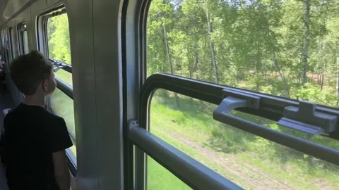 A boy on a train. Rear view of a boy riding a train and looking out the window. Video stock 243628493
