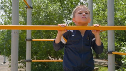 Boy is training on a horizontal bar outside. Video stock 276835601