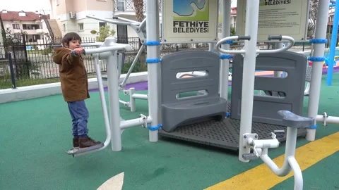 Boy trains alone on exercise machines outdoors Stock Footage 136896454