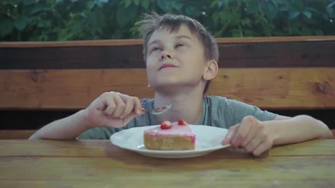 The boy tries the cake, enjoying the process. gives a thumbs up. positive Stock Footage 170822850
