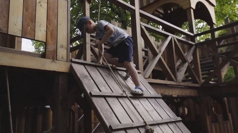 The boy tries to descent the cable-rope in the park Stock Footage 94346648