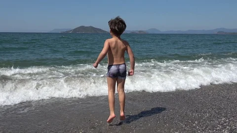 Boy tries to get into the cold sea but changes his mind Stock Footage 106476996
