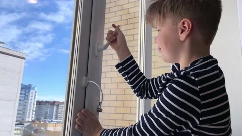 Boy tries to open the window standing on the windowsill on a high floor. Stock Footage 235718144