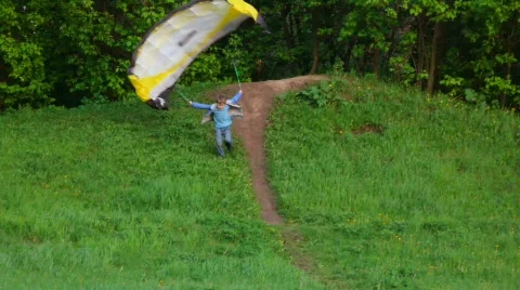 Boy trying to start kite by running down from hill, but fall over Stock Footage 536323