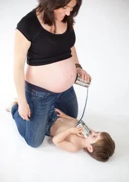 Boy trying to talk to his future brother inside the belly of his pregnant mom. Stock Photos