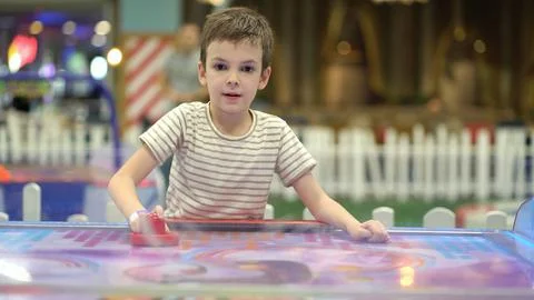 Boy trying to win in the game of air hockey on the playground Stock Photos