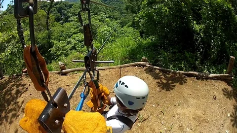Boy turns to father while riding on zipline over jungle in Costa Rica. Video stock 99369748