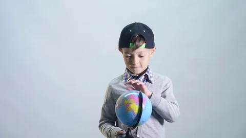 Boy turns the globe on finger and choose country Stock Footage 76607070