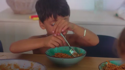 Boy twirling spaghetti around fork during family meal at dining table captu.. Stock-Footage 342828412