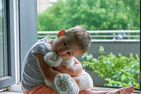 Boy of two years sitting by the window and hugs a toy Bunny. rainy weather Stock Photos