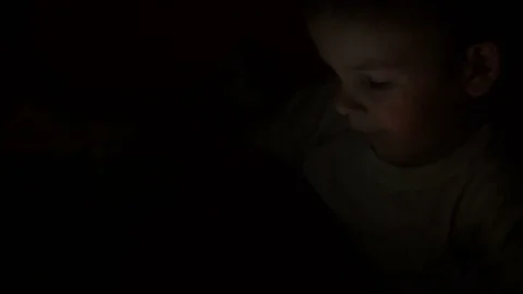 Boy of two years watching cartoons on his tablet at night. Stock Footage 84697377