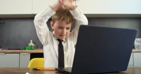 Boy types on laptop looking at screen with satisfied expression Stockbeeldmateriaal 314722432