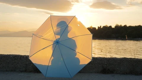 Boy with umbrella playing on sunset background. Kid walking along quay. Happy Video stock 119770831