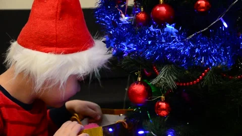 Boy under Christmas tree at home Xmas  drink hot chocolate Kids open presents 動画素材 166552770