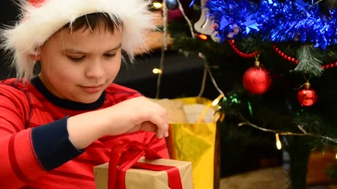 Boy under Christmas tree at home Xmas  drink hot chocolate Kids open presents 動画素材 166552790
