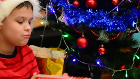 Boy under Christmas tree at home Xmas  drink hot chocolate Kids open presents Stock Footage 166552798