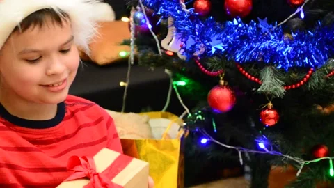 Boy under Christmas tree at home. Little boy in knitted sweater with Xmas orname Stock Footage 166552799