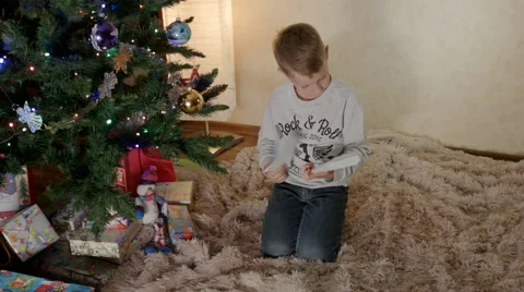 Boy under new year tree puts a letter to Santa in an envelope Stock-Footage 67727338