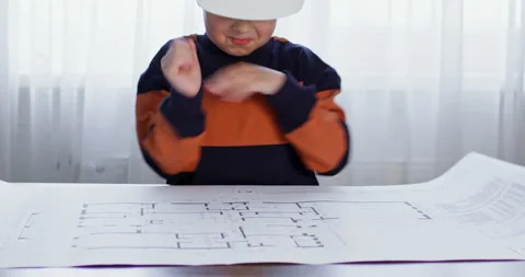 The boy unfolds a paper drawing of the plan of the house Vidéo 236478077