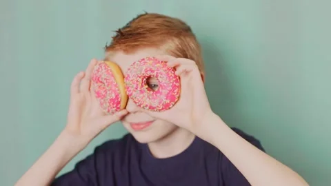 Boy uses donuts like the eyes Stock Footage 232810165