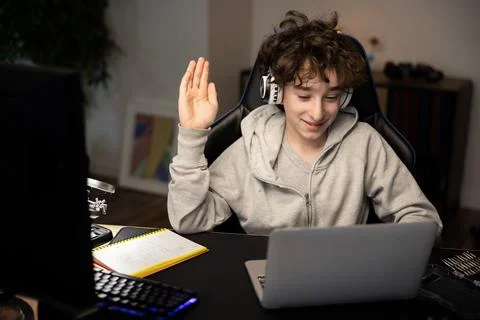 Boy uses a laptop computer with video conferencing software to talk to a group Stock Photos