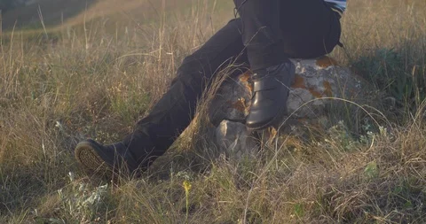A boy uses a mobile phone while sitting on a rock in the nature Stock Footage 90801756