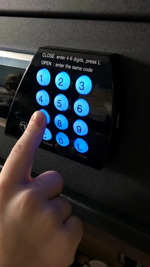Boy uses modern electronic safe entering combintaion of four numbers to lock a Stock Footage 126322737