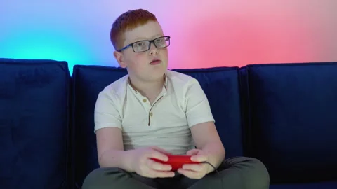 Boy uses old controller to play video game. A boy plays old 8 bit game. Cozy Stock Footage 194726733