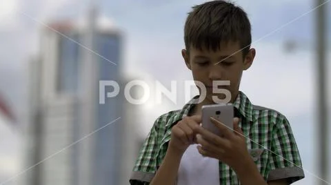 Boy uses the phone, dials a message, and keeps in correspondence Stock Photos