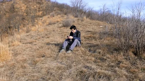 Boy uses the phone for texting in the mountains Stock Footage 59998981