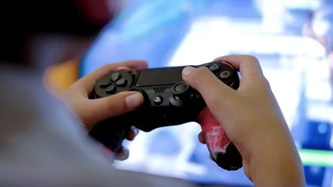 Boy uses ps4 controller to play video game Stock Footage 121697624