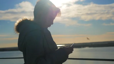 The boy uses a smartphone at sunset Stock Footage 83829666
