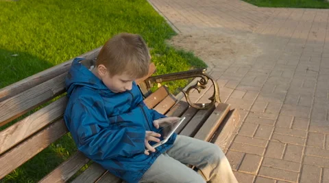 Boy uses tablet pc outdoors in the park Stock Footage 62790295