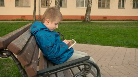 Boy uses tablet pc outdoors in the park Stock Footage 62790359