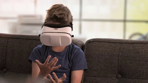 Boy uses virtual reality headset on the couch Stock Footage 79573786