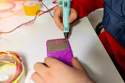 Boy using 3D pen. Happy child making flower from colored ABS plastic. Creativ Stock Photos