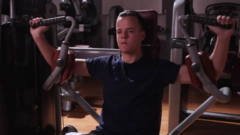 Boy using bodybuilding machine in gym - close up Stock Footage 154386103
