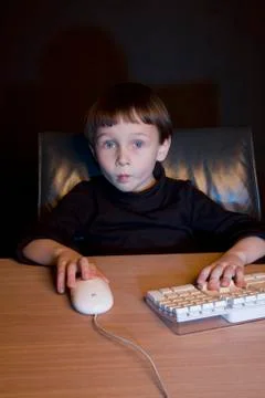 A boy using a computer mouse and keyboard Stock Photos