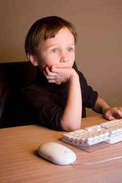 A boy using a computer mouse and keyboard Stock Photos