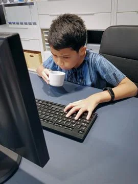 Boy Using Computer While Drinking a Cup of Tea Foto stock