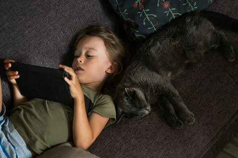 Boy using digital tablet computer playing games or watching cartoons at home. Stock Photos