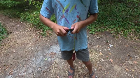 Boy using fire starter to create sparks outdoors in the forest. Close-up of Stock Footage 316141393