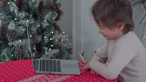 Boy using his laptop sitting at the table near the Christmas tree Video stock 70390274