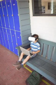 Boy using laptop and virtual reality glasses while sitting on bench 写真素材