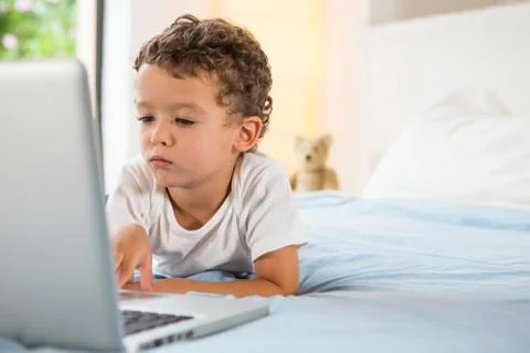 Boy using laptop on bed Stock Photos