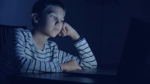 Boy using laptop computer, watching video, play at night Stock Footage 128031957