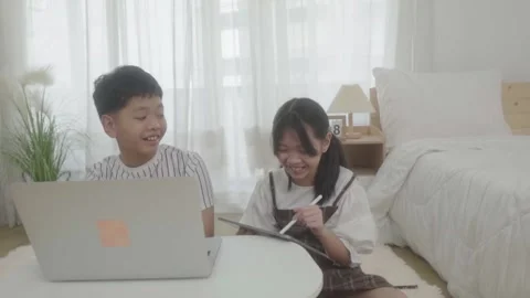 Boy using laptop looking at girl using pen write tablet in bedroom. Stock-Footage 240800262