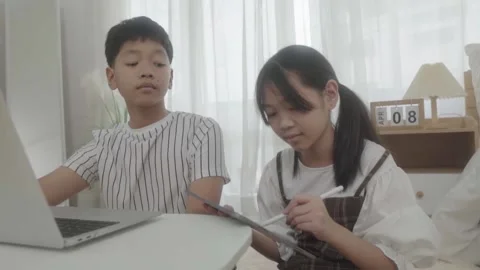 Boy using laptop looking at girl using pen write tablet in bedroom. Stock-Footage 240800264