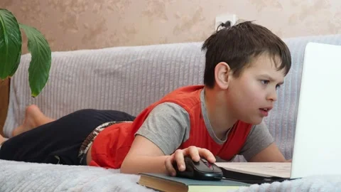 Boy using a laptop playing online games blogging, studying online 库存影片 148630519