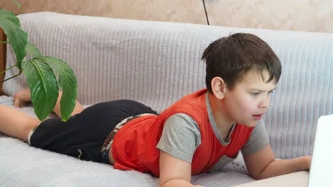 Boy using a laptop playing online games blogging, studying online Vidéo 148630630